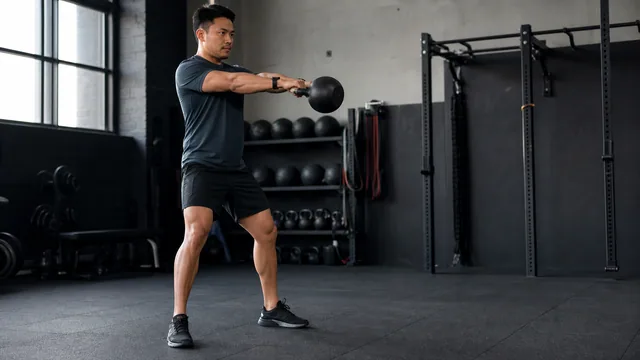 Athlete completing a controlled kettlebell interval in a spacious gym while wearing a smartwatch